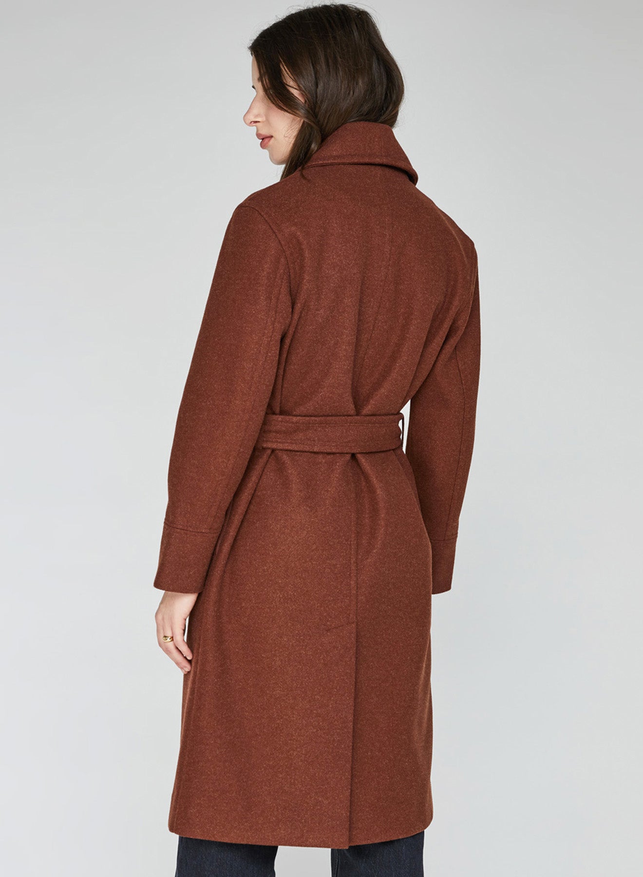 A woman wearing a belted wool look coat.